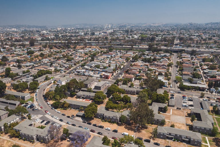 Drone shot capturing the sprawling urban landscape of a Los Angeles neighborhood under clear skies.